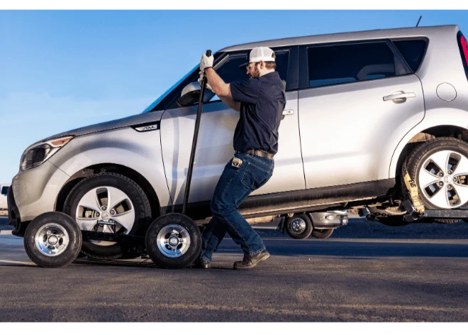 Person using a pry bar to lock in the In the Ditch X-Series Dolly under the wheel of a car - ITD2790-P