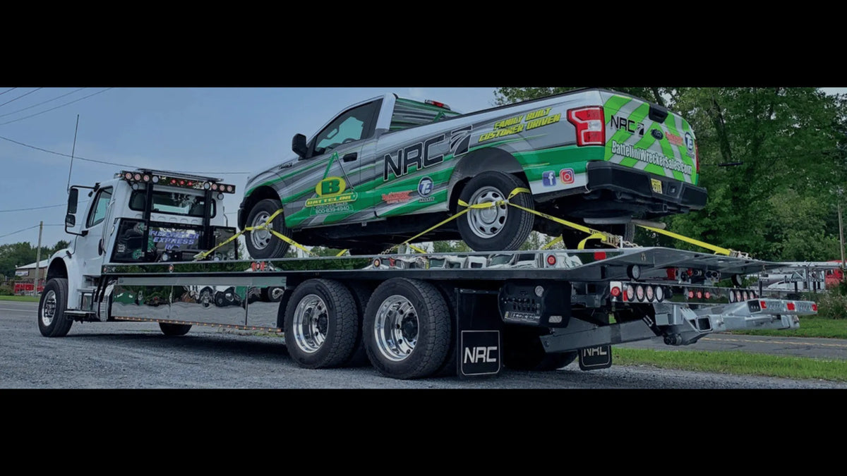 a pickup truck secured to the bed of an NRC car carrier tow truck