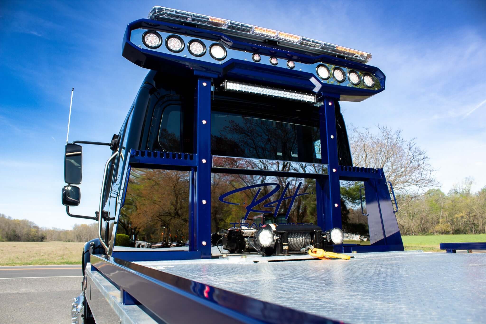Close-up of a blue towing truck with a custom light bar and reflective panel, showcasing its robust design and features.