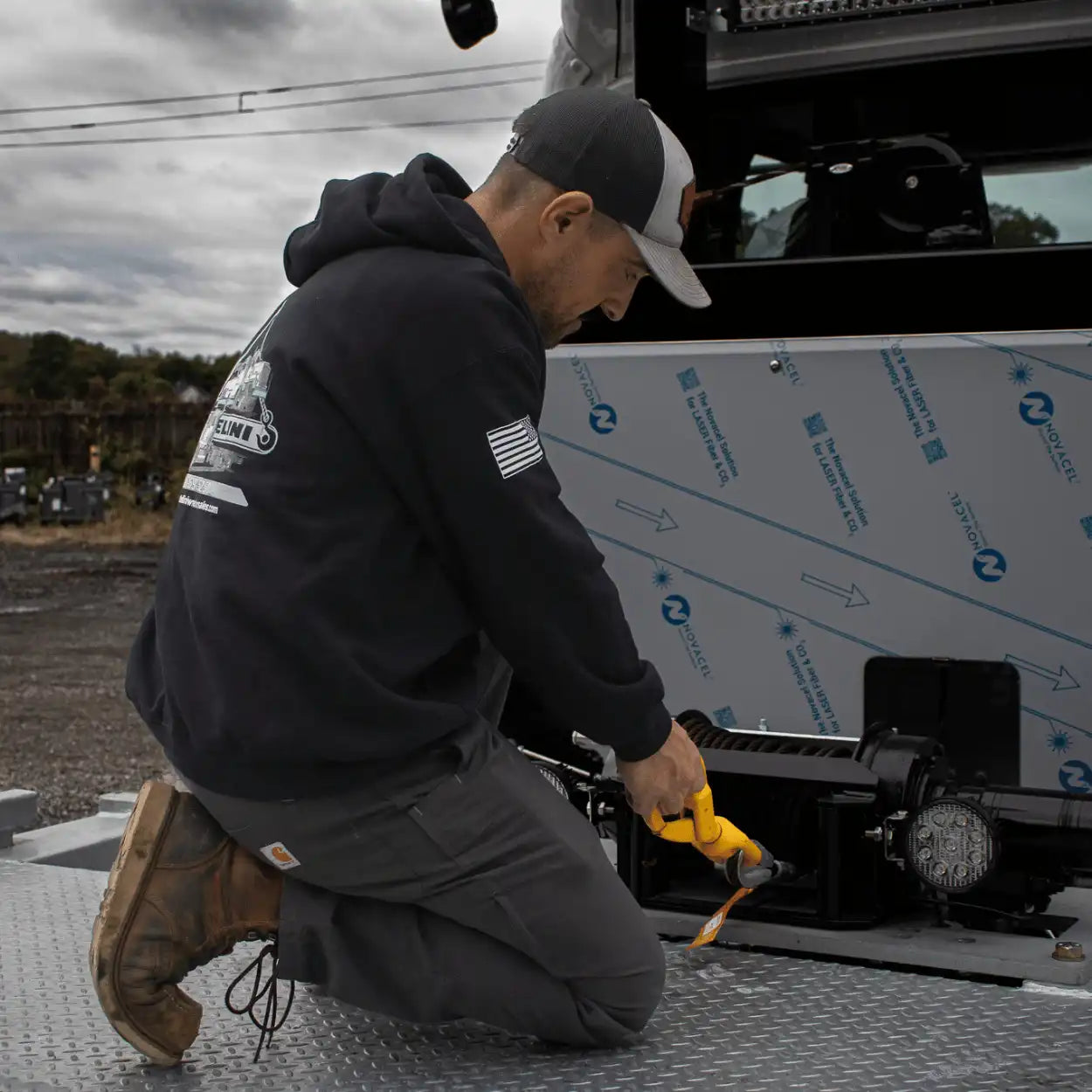 pulling out a winch cable wearing a battelini trucking hoodie