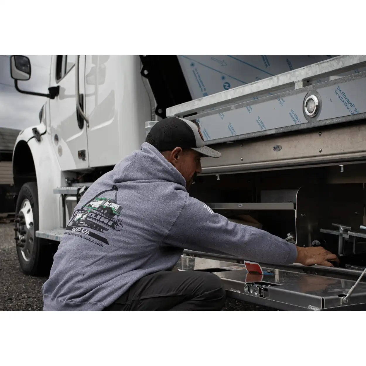 Person working on a truck bed cover with a graphite heather battelini trucking hoodie