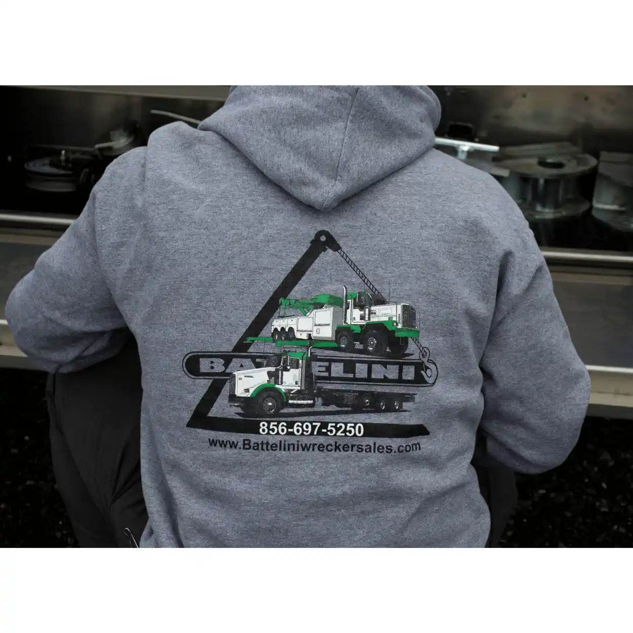Person wearing a gray hoodie with Battelini wrecker sales logo on the back.