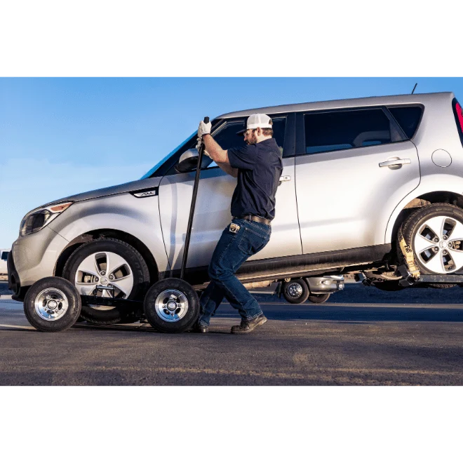 Person using a pry bar to lock in the In the Ditch X-Series Dolly under the wheel of a car - ITD2790-P
