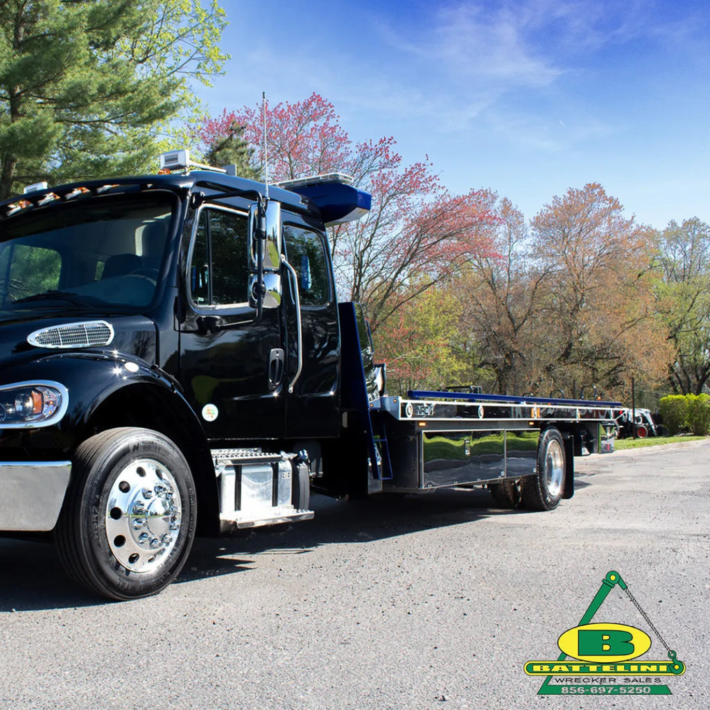 Black Freightliner M2 rollback with NRC deck, blue side rails, and polished stainless steel deck side trim