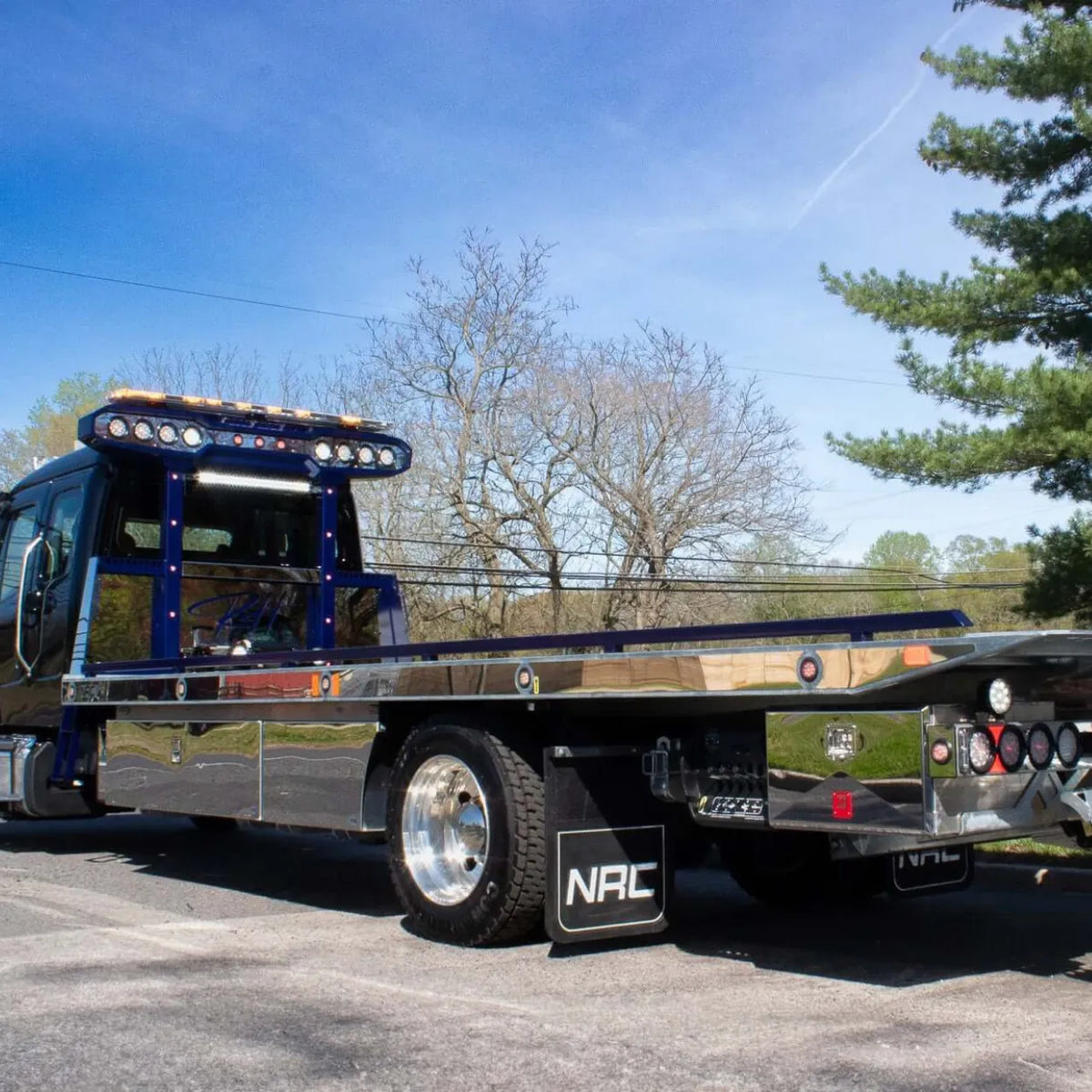 Polished stainless steel side trim on NRC carrier deck with round marker lights, blue rails, and stainless toolboxes