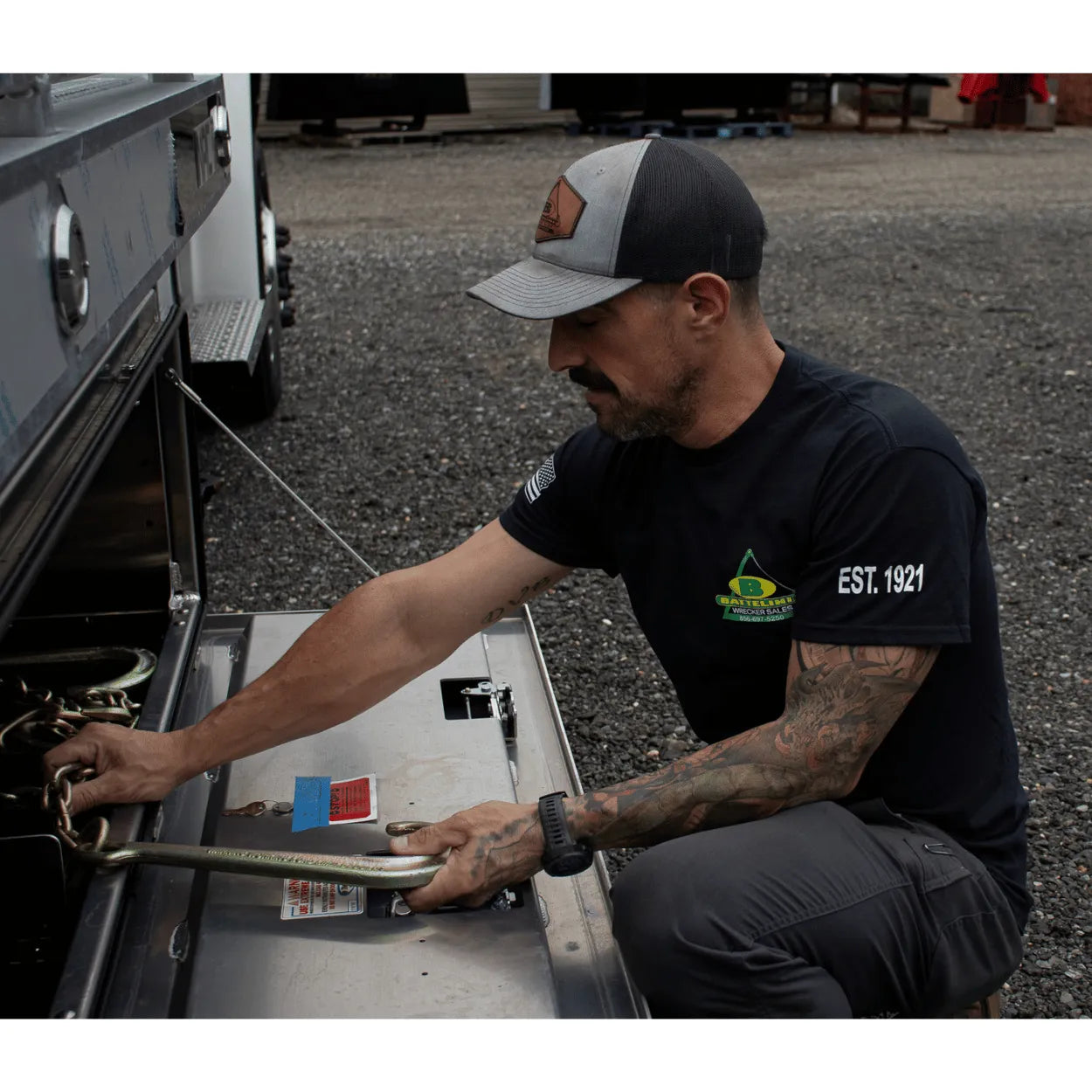 pulling chain out of a toolbox wearing Battelini trucking t-shirt