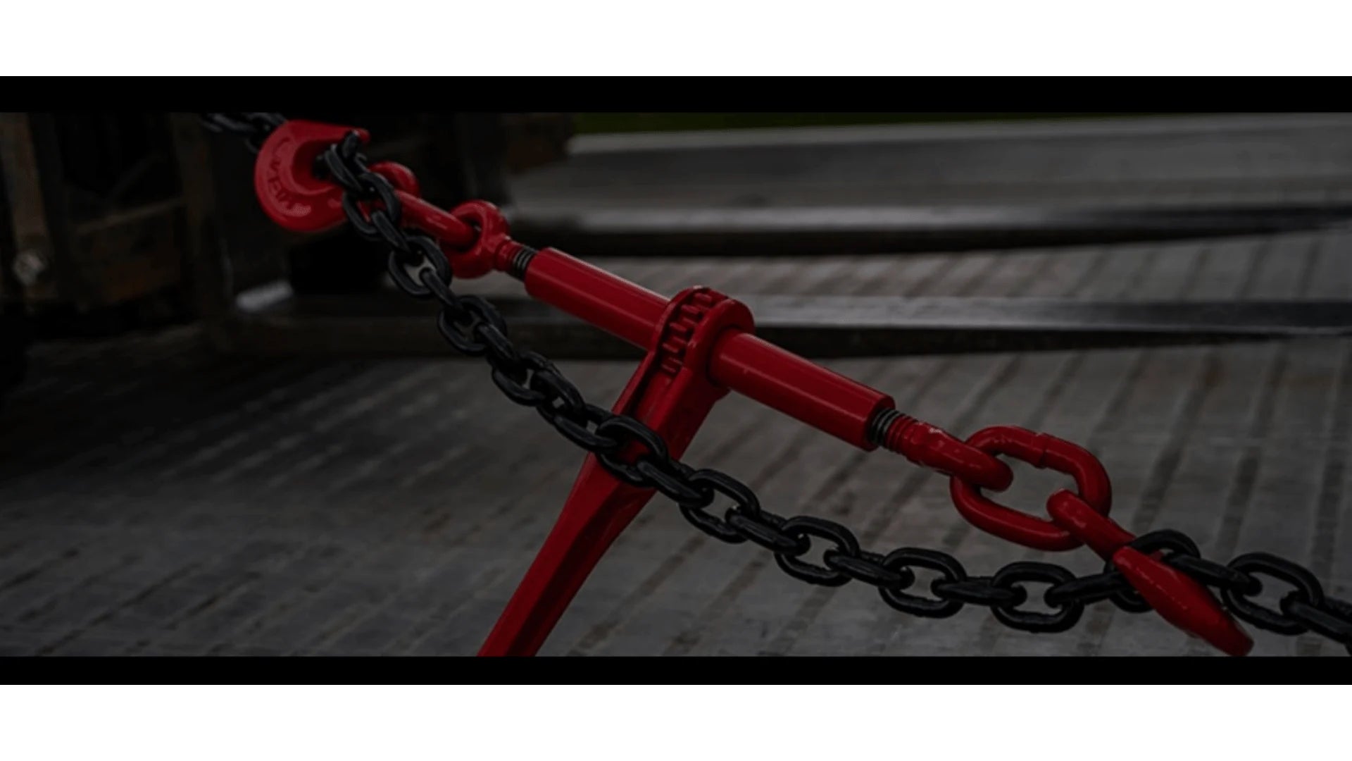 ratchet binder tightening chain to prepare a forklift for transport