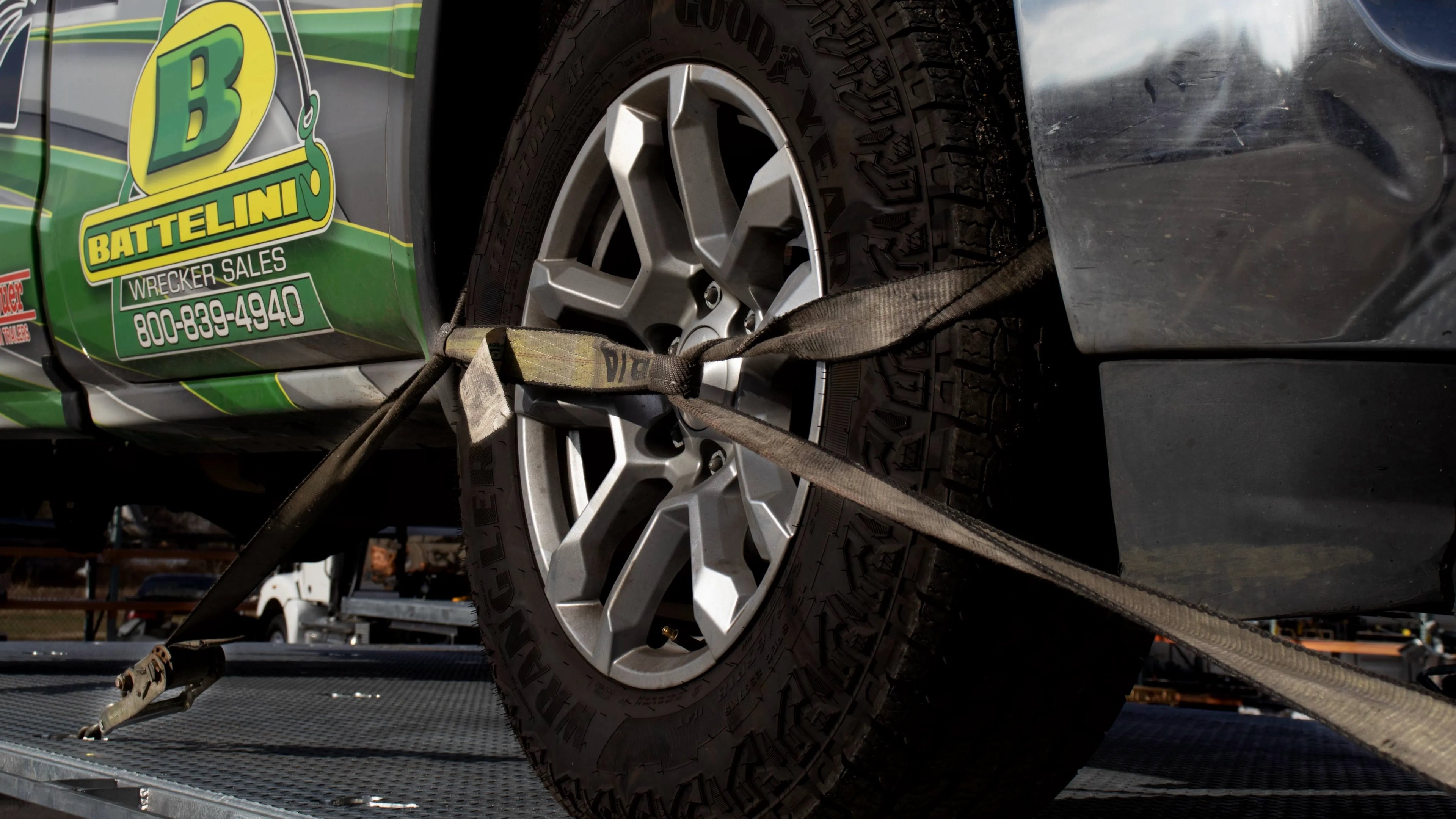 a truck safely secured to a tow truck bed using b/a products tire tie-down straps